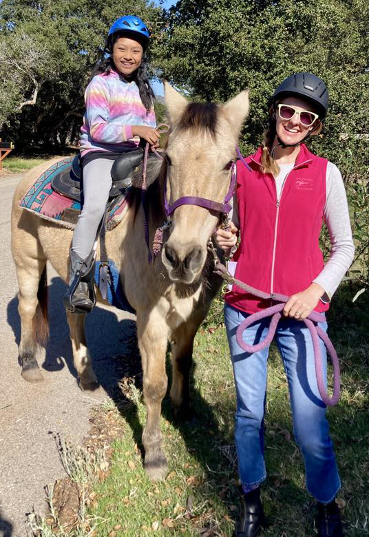 A woman and girl enjoy horseback riding