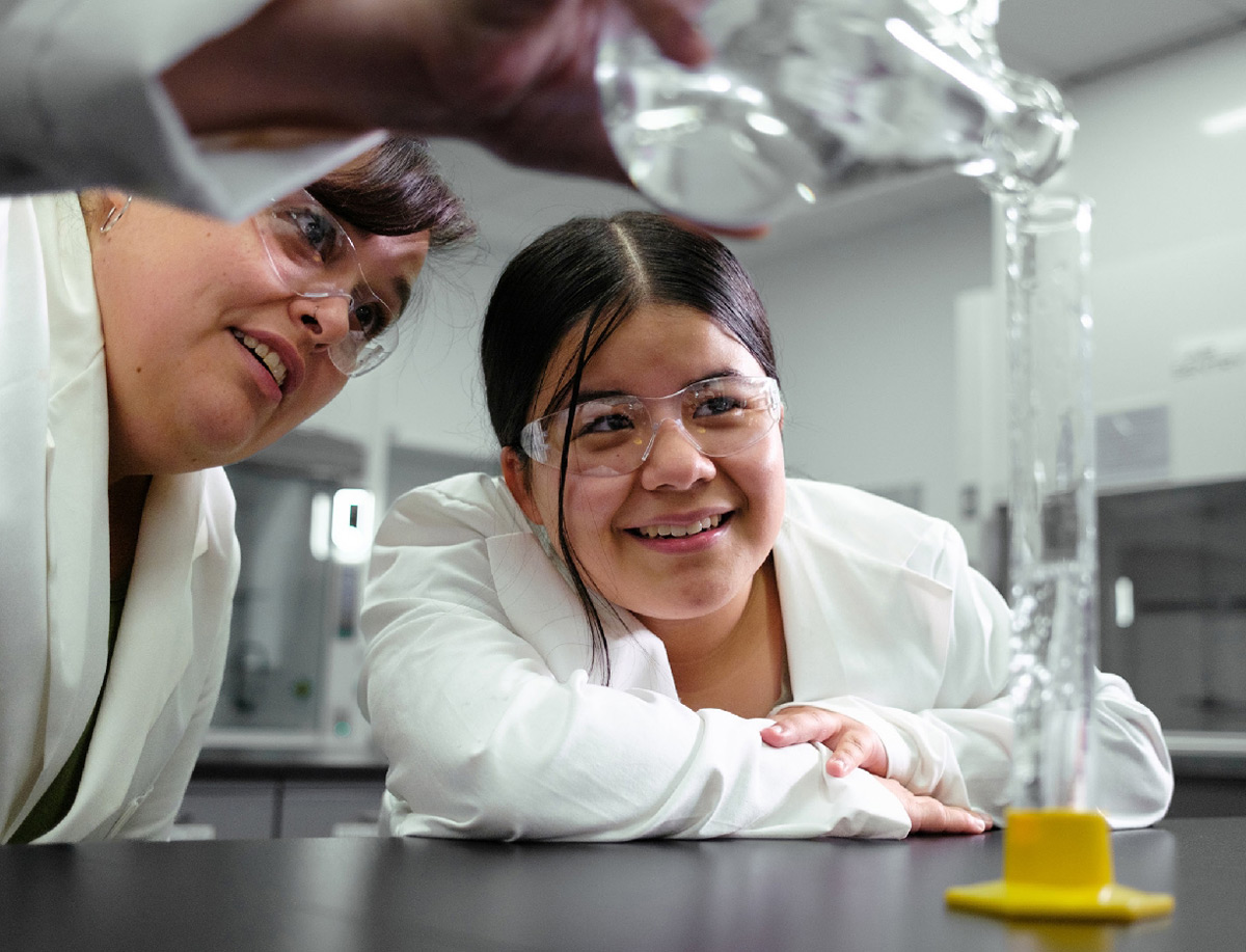 Student and instructor wearing safety goggles while conducting a science experiment in a laboratory.